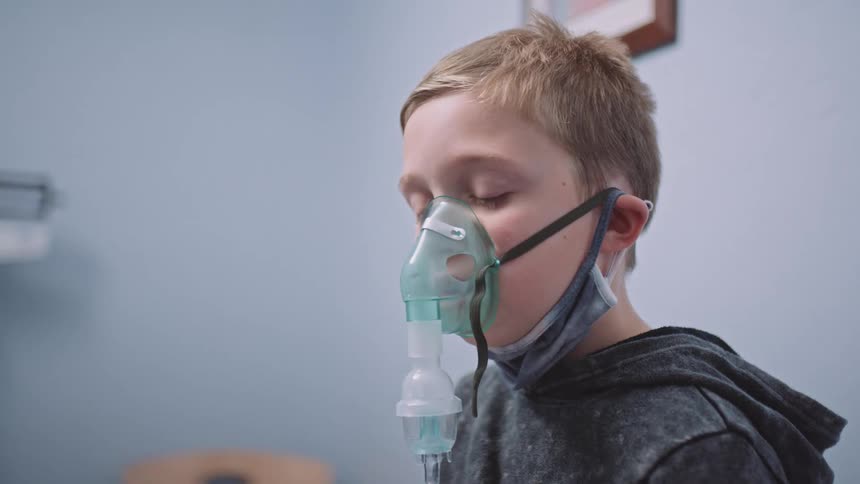 A doctor puts a breathing mask on a boy