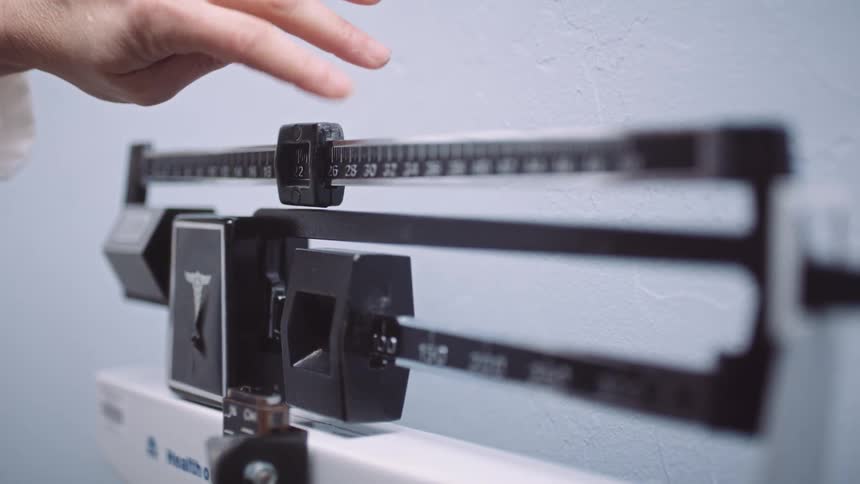 A nurse moves balances on a scale