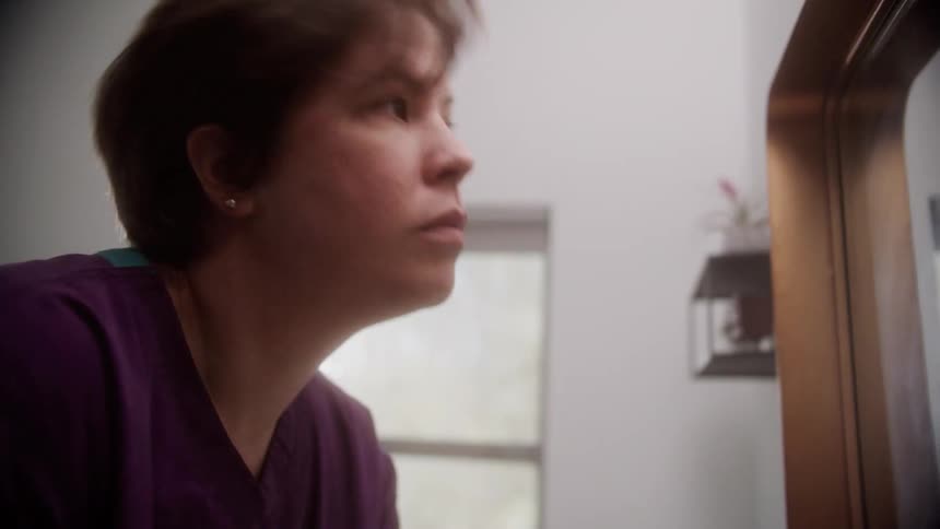 Young woman washes her hands with liquid soap on the bathroom at home while looking at her face in the mirror