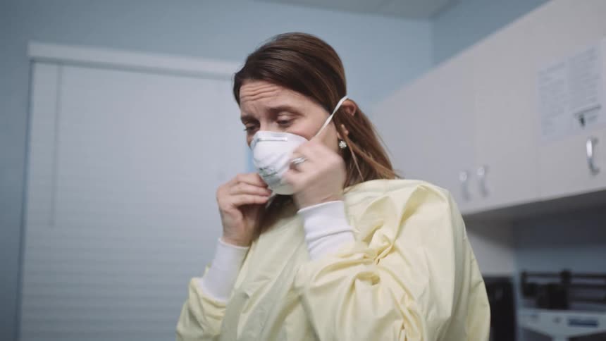 A doctor in a clinic puts on glasses and a mask