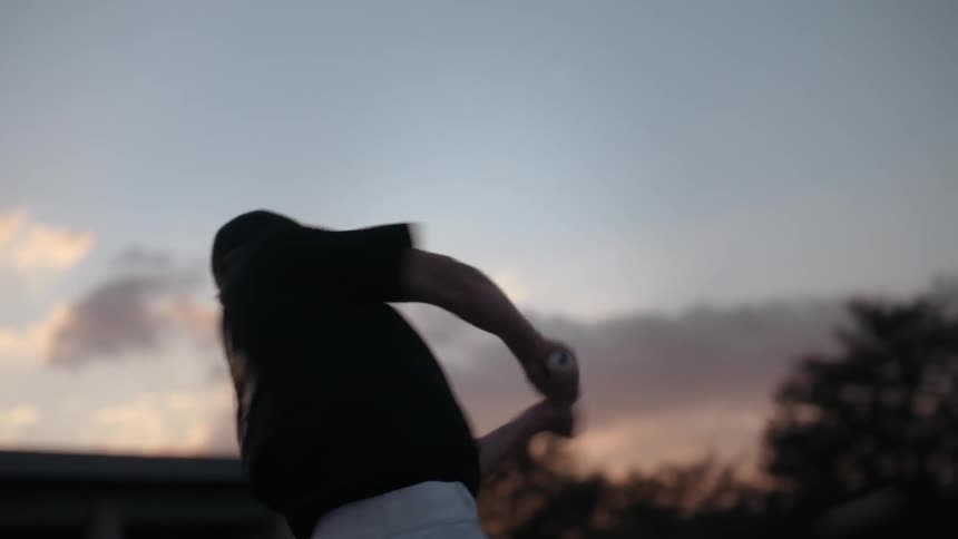 A baseball player swings at a ball at dusk or dawn