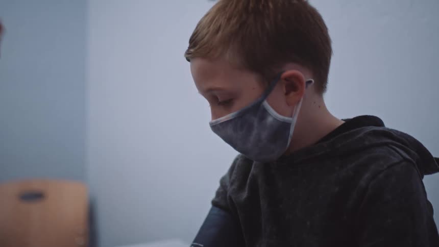 A female doctor uses a blood pressure monitor and stethoscope to check the blood pressure of a boy