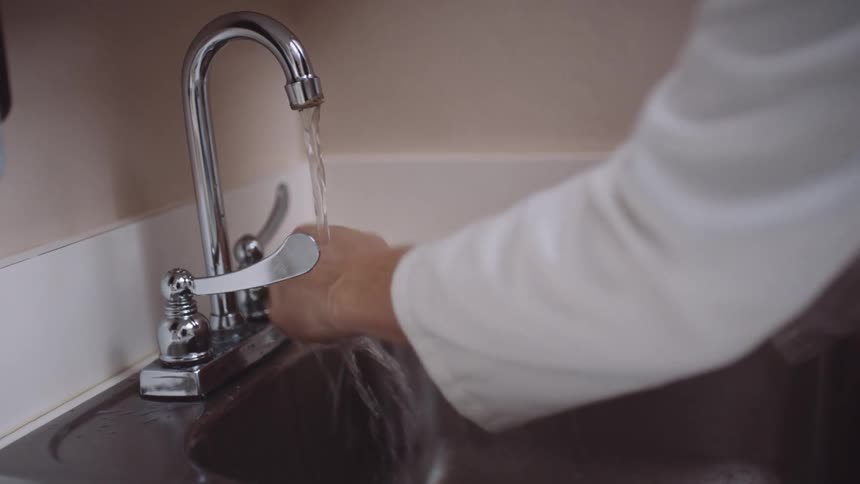 A doctor washes and dries her hands in a clinic