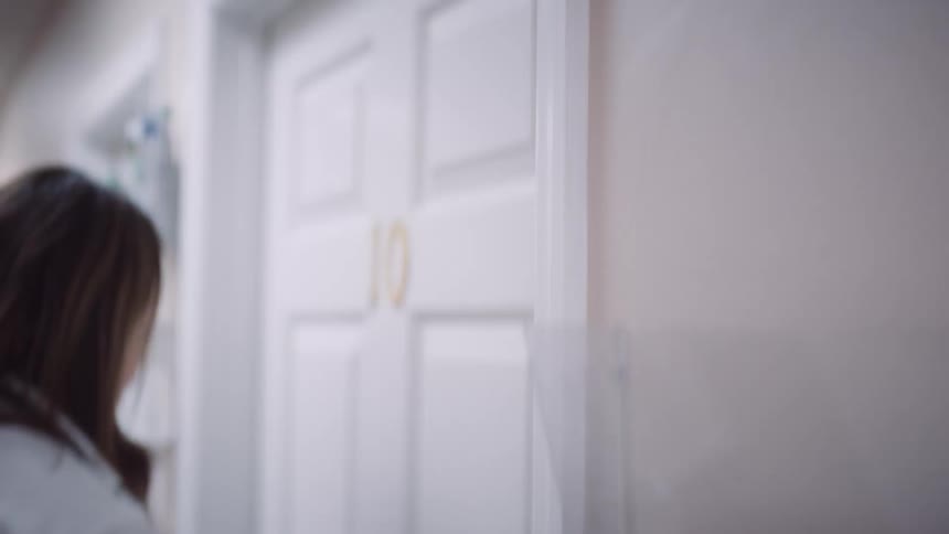A female physician enters an examination room at a small medical clinic