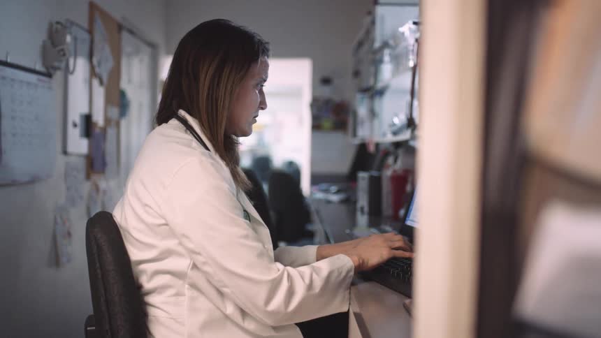 A doctor sitting at a computer typing