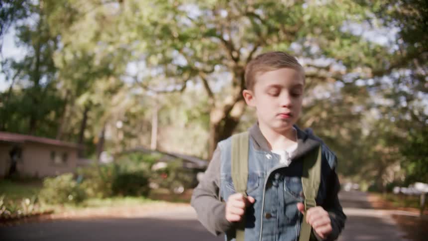 A child is walking through a neighborhood in spring