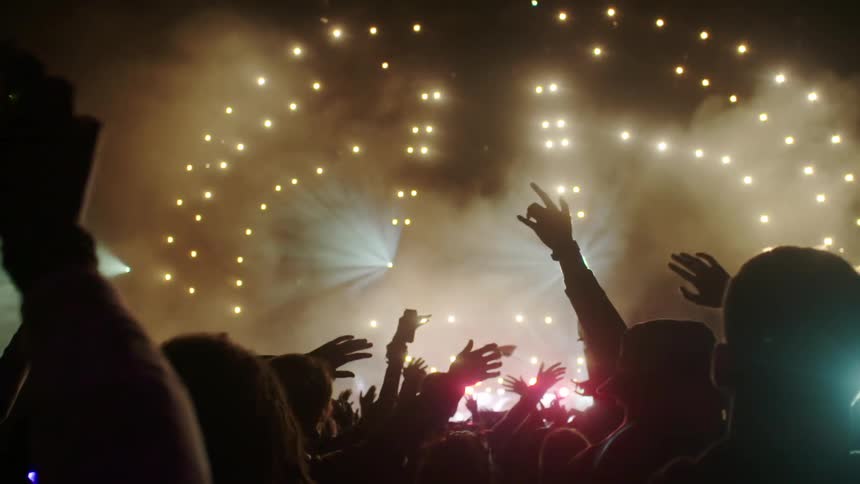 An audience waves their arms at a concert