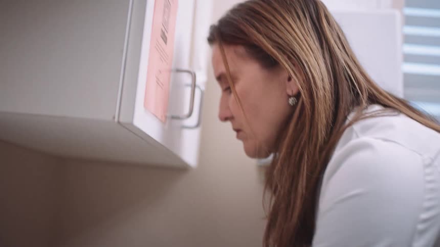 A female physician thoroughly washes her hands inside of an exam room