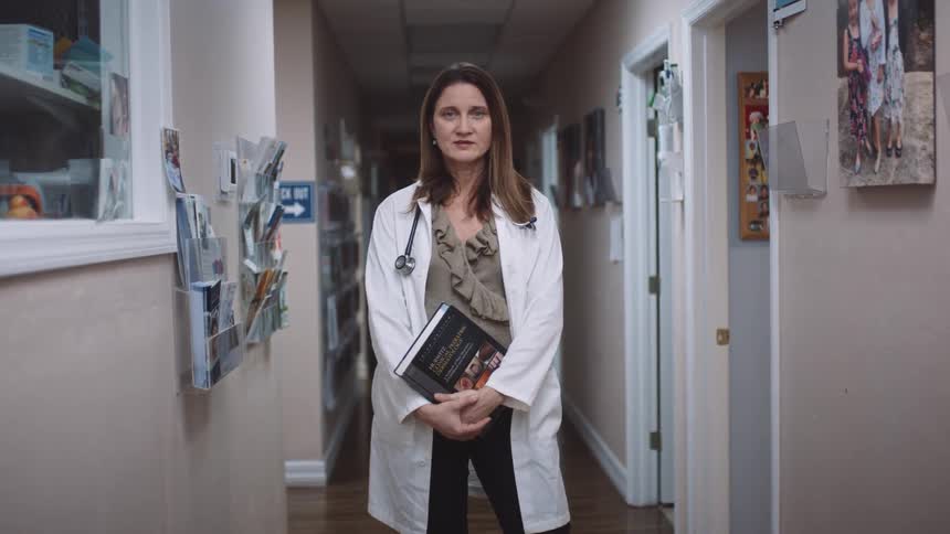 A doctor standing in a hallway holding a book