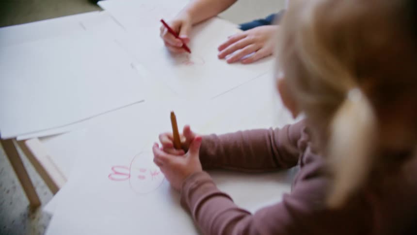 Two children drawing with crayons in a room