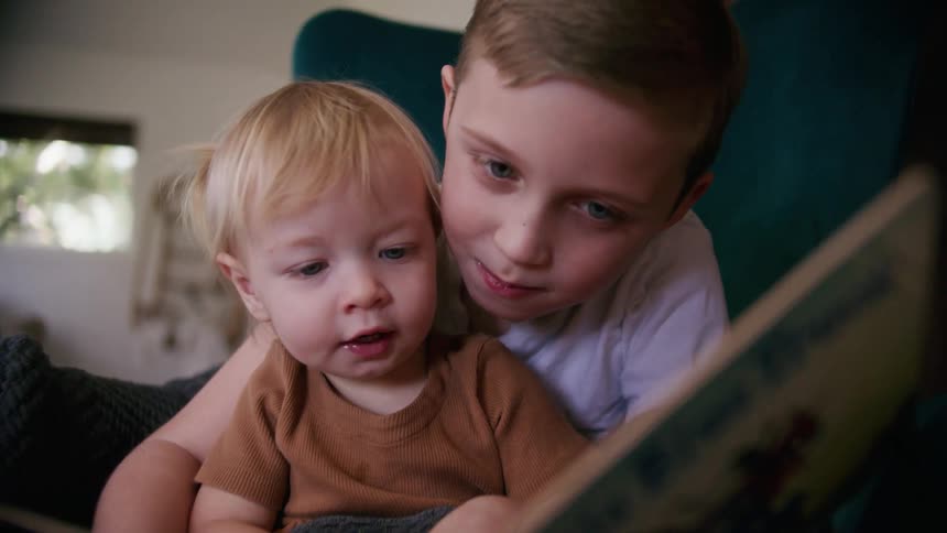 A child and toddler reading together