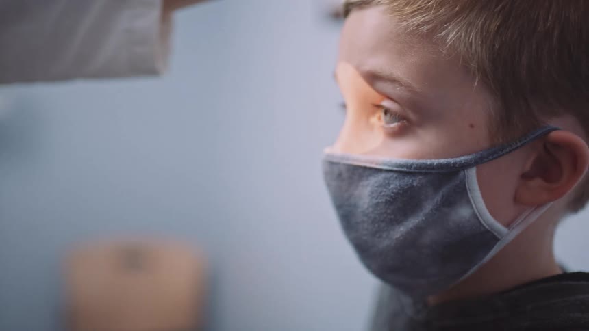 An eye doctor looks in a young boys eyes as she examines him