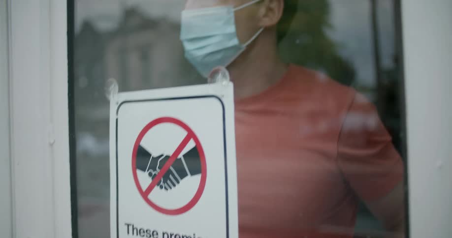 A person hanging a sign on the door of a store