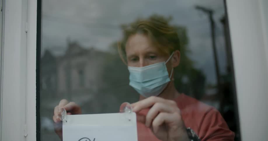 A man putting up a sign to wear masks