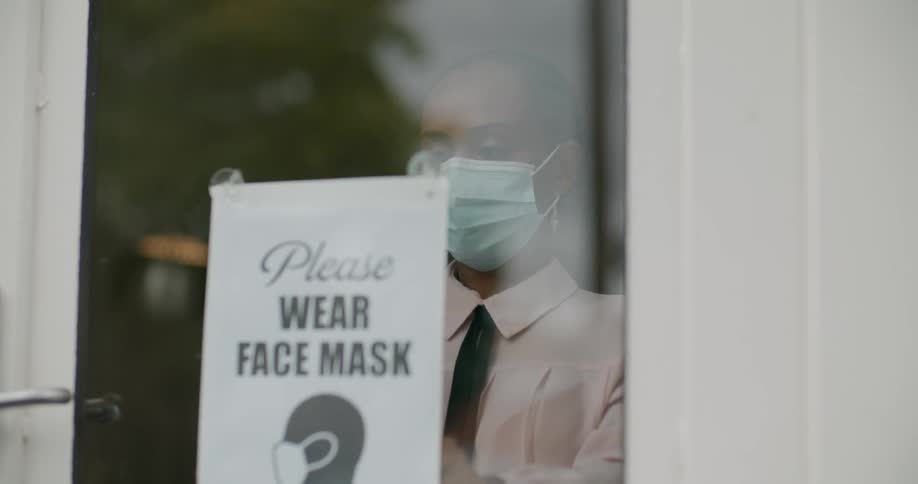 A woman putting up a sign to wear masks