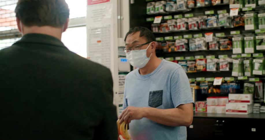 A man buying a banana at a store counter
