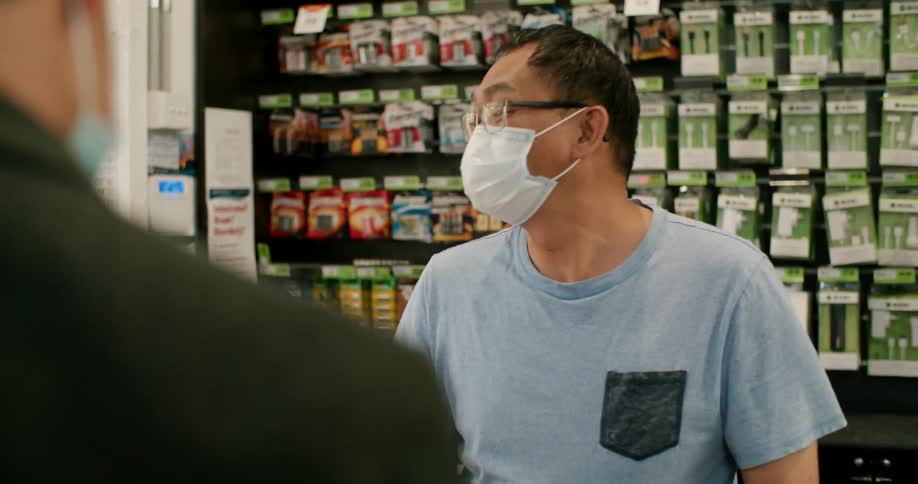 A man selling things at a store to a client