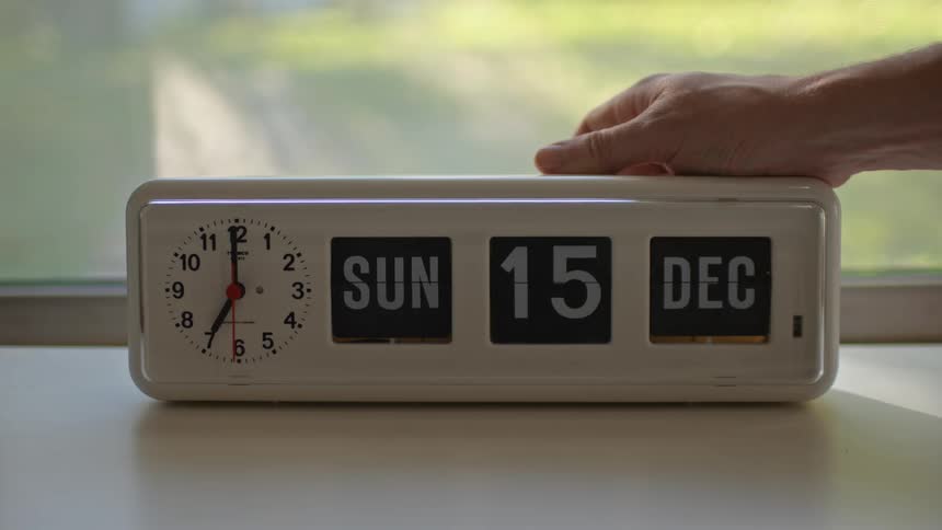 A person changes the date on a manual alarm clock