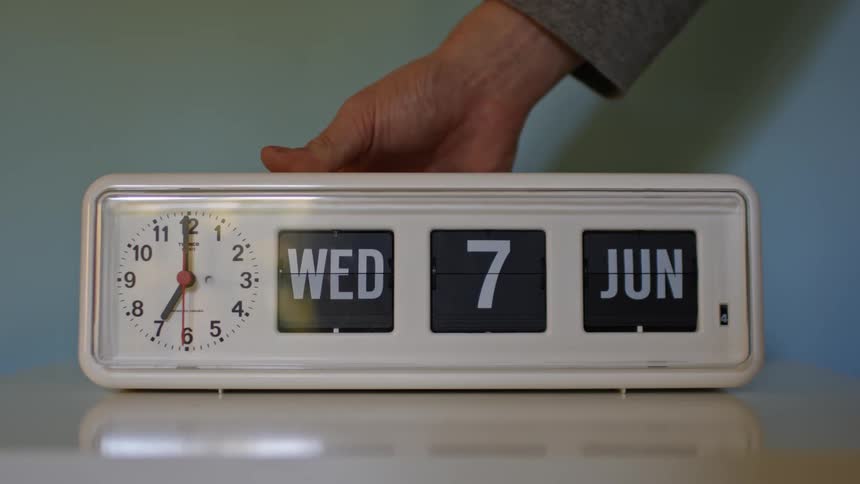 A person changes the date on an alarm clock