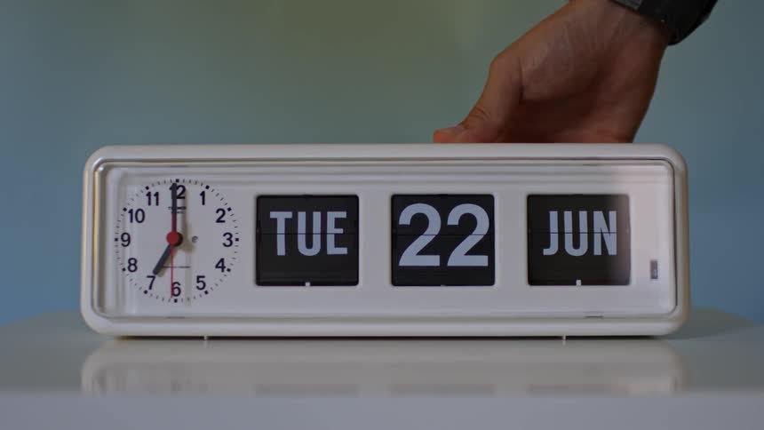 A hand is on an alarm clock