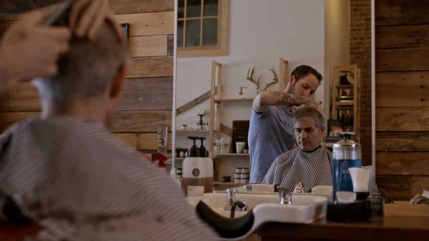 A man cuts another man's hair in a barber shop