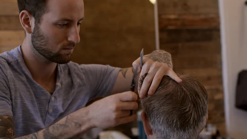 Bearded barber cutting a customer's hair