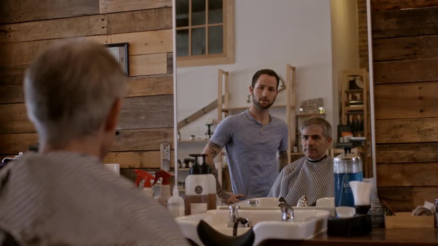 A hair stylist chats with a man at a salon