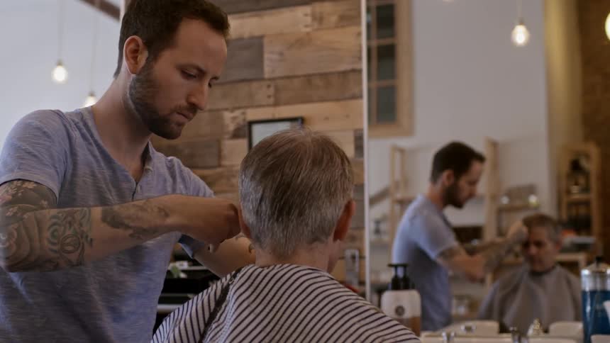 Man getting a haircut from a bearded barber
