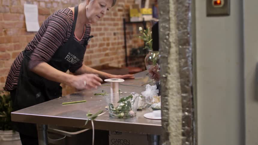 A florist clears flower leaves and stems from a table