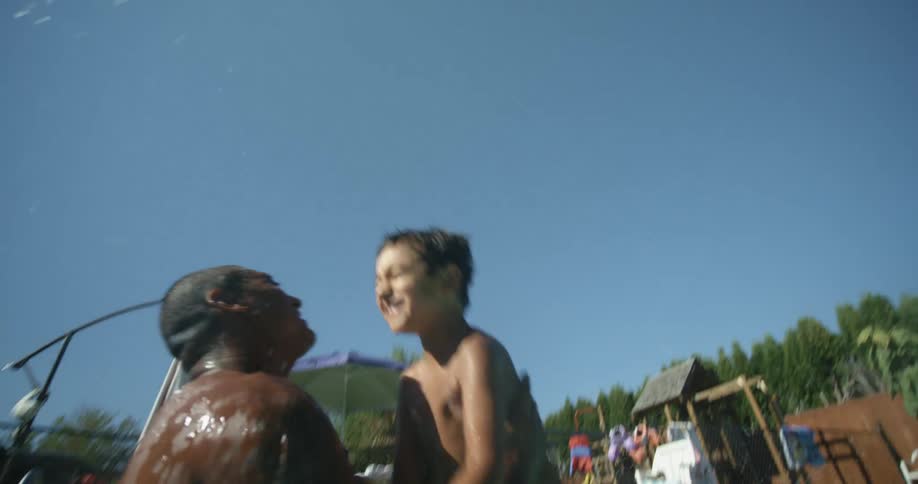 A father is playing with his son in an outdoors pool