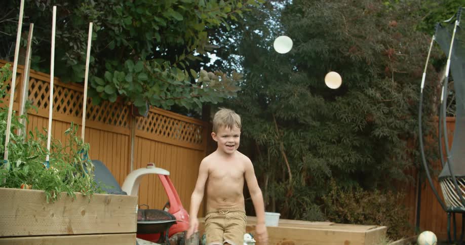 A young boy throws two water balloons at his dad while they play in their backyard