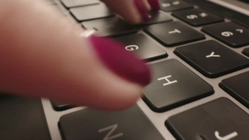 Fingers tap on a laptop keyboard