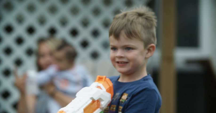 A child playing with a squirt gun in a yard