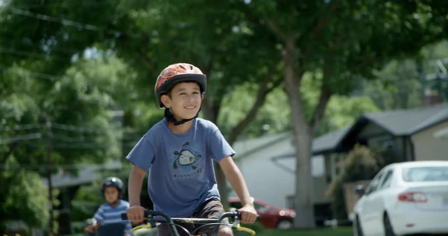 Two young boys ride their bikes down a neighborhood street