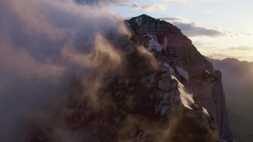 A mountain range with ice and snow with the sky and clouds in the background