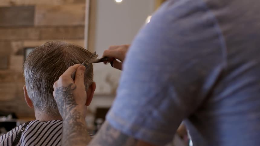A man is sitting in the barbershop getting his haircut