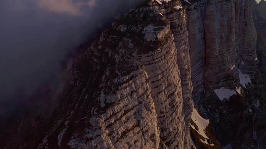 A mountain range with ice and snow with the sky and clouds in the background