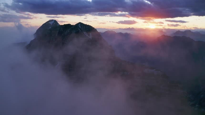 A mountain range with ice and snow with the sky and clouds in the background