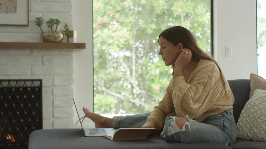 A woman writing in a book sitting on a couch