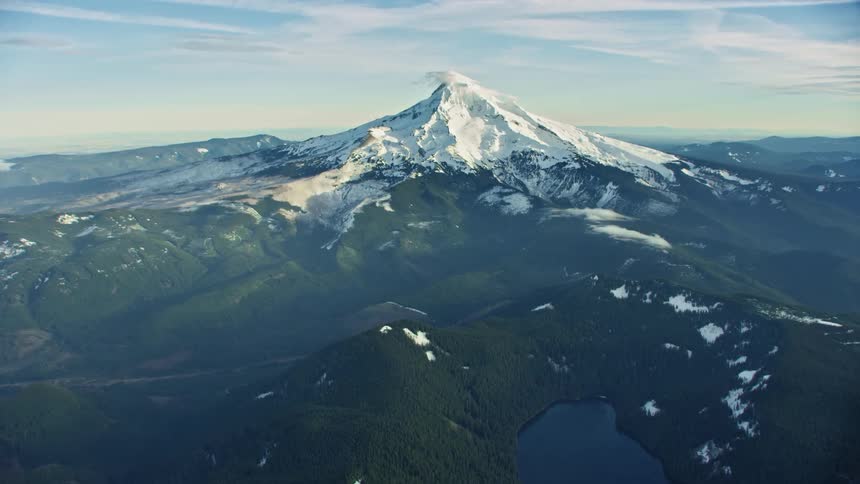 Sunset aerial view of the snow covered mountain peak Mount Hood in the forest with an alpine lake