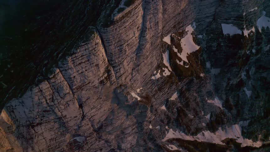 Aerial view of the snow covered steep cliffs on a mountain range at morning