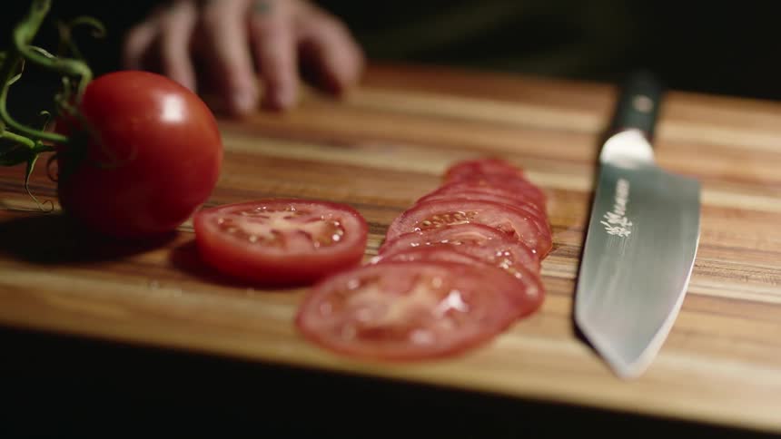 Sliced tomatoes sitting on a cutting board next to a knife