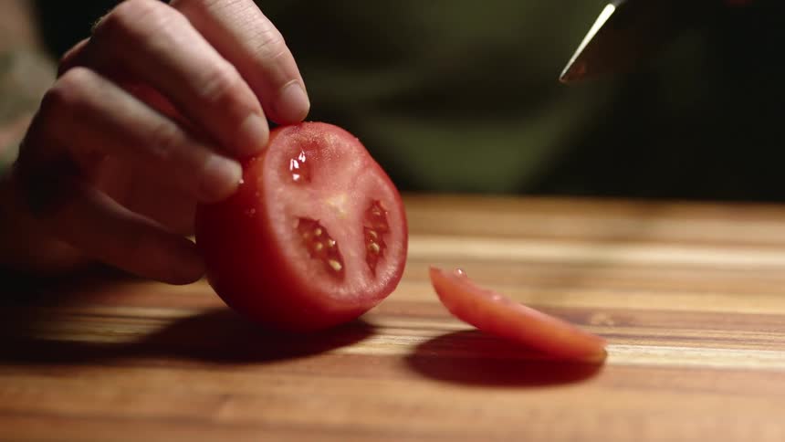 A person slices a tomato with a knife
