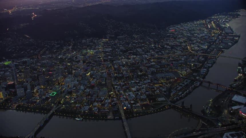 Awesome blue hour high altitude aerial of downtown Portland Oregon as the camera slowly tilts down and focuses on the burnside bridge and welcome to Portland sign
