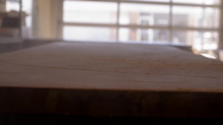 A person pours sawdust on a table