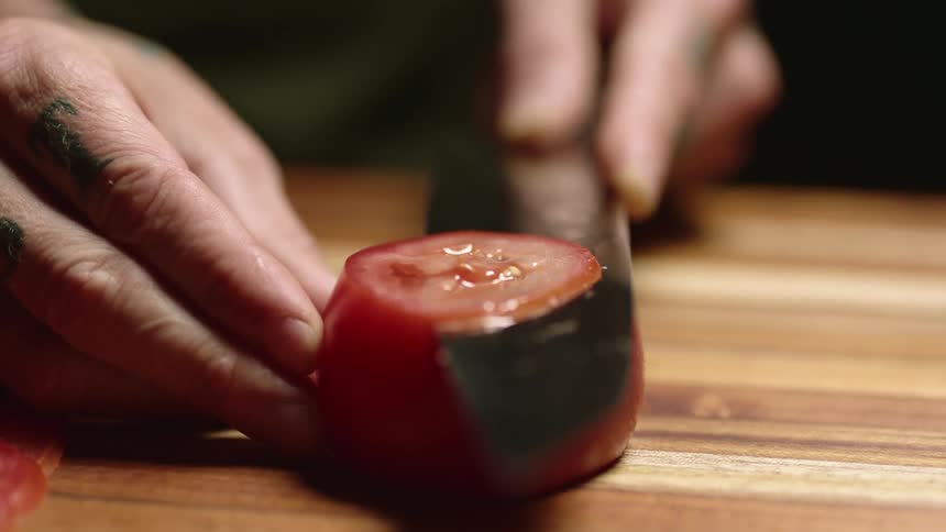 A close up of a person cutting a tomato