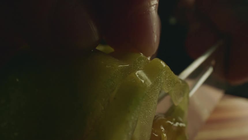 A person dicing fresh produce with a sharp knife on a wood cutting board