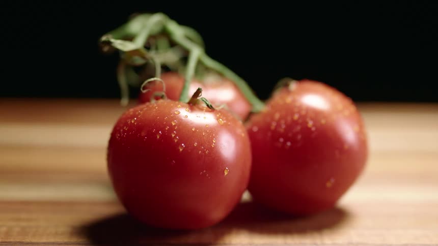 Tomatoes are on display on top of a wood counter