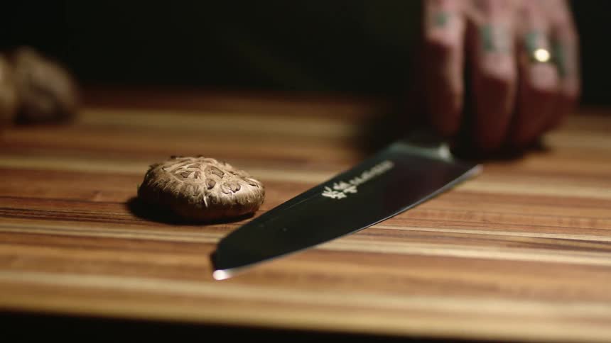 A person picking up a knife from a cutting board and touching a confectionery