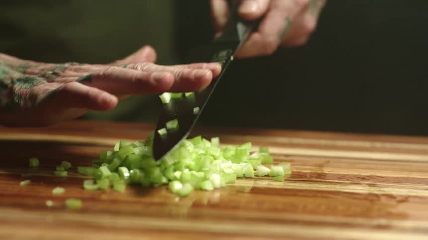 A man is cutting onions with a knife indoors